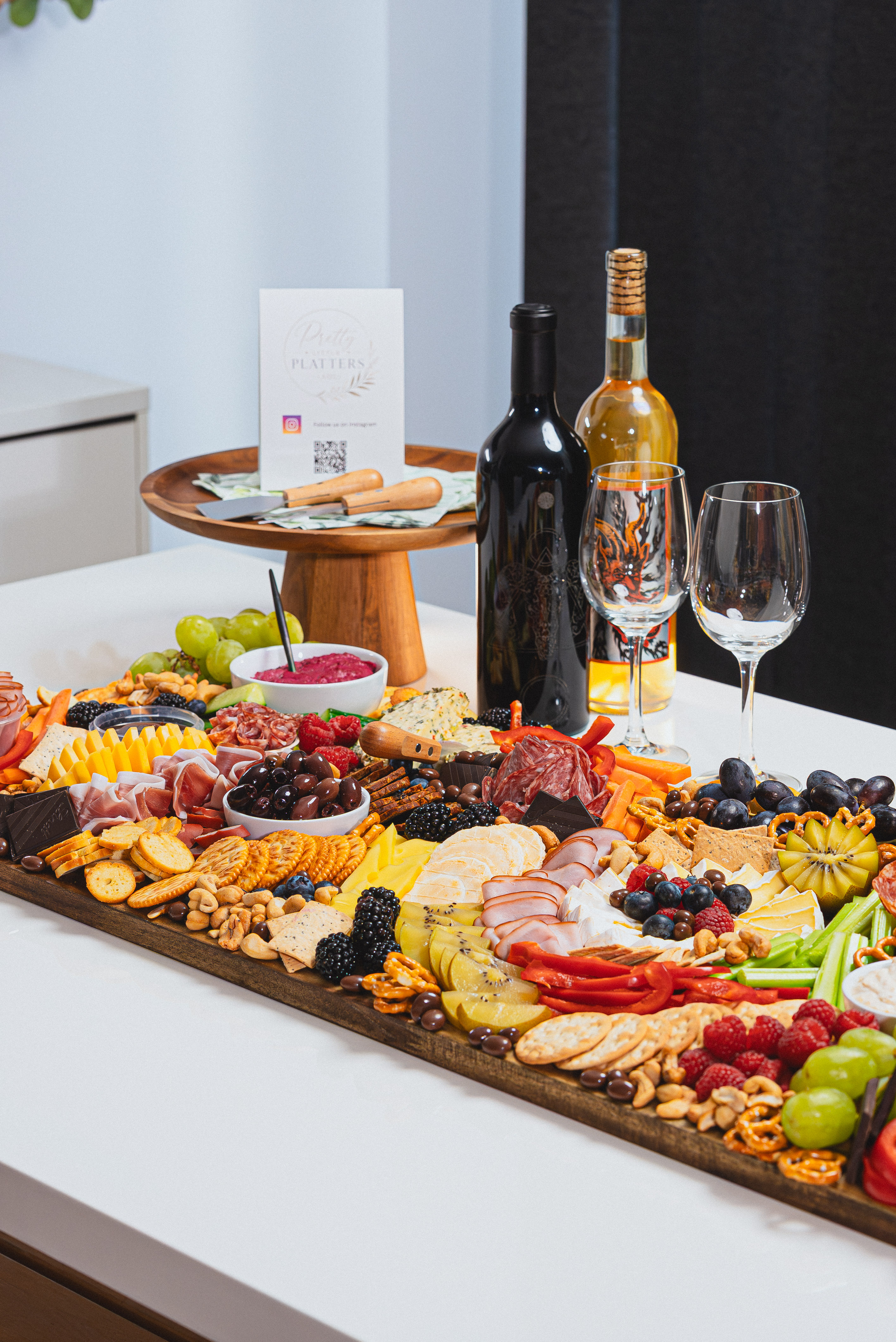 A styled grazing platter with fruit, cheeses, crackers, and flowers